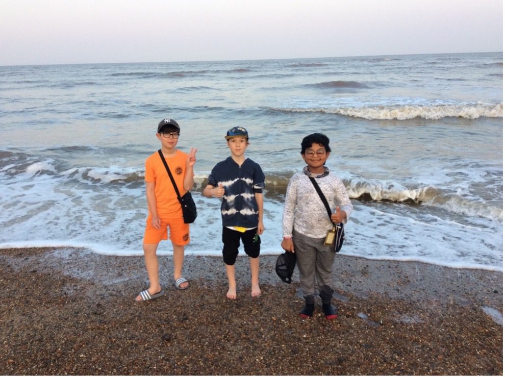 three Year 6 boys standing on the beach